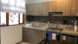 A compact kitchen with wooden cabinets, a gas stove, a sink, and a tiled backsplash. - Huanchacostudio/kingbed/balcony/tv/wifi (Huanchaco)