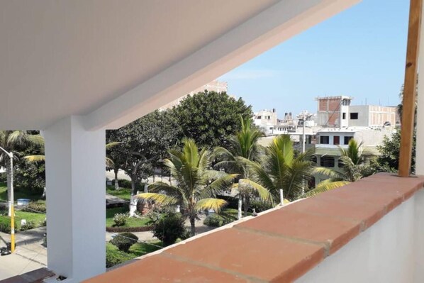 Un balcón con vista a una zona residencial, con casas y palmeras.