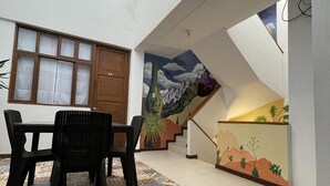A dining area with a table and chairs, a staircase with a mural, and a door marked with the number 21. - Huanchacostudio/kingbed/balcony/tv/wifi (Huanchaco)