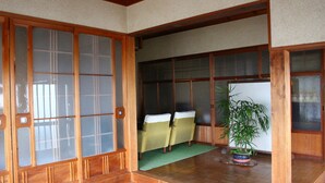 Ein traditioneller japanischer Raum mit Schiebetüren, einem Tatami-Bodenbelag und einer Zimmerpflanze im blauen Topf.