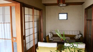 Ein traditioneller japanischer Raum mit Schiebetüren, einem Sofa und einem kleinen Tisch mit einer Pflanze.