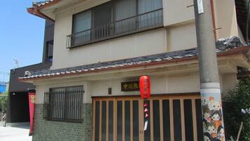 Un edifici tradicional japonès amb teules, una porta de fusta i un fanal vermell.