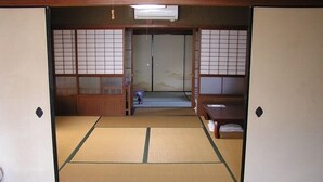 Ein traditioneller japanischer Raum mit Tatami-Böden, Schiebetüren und einem niedrigen Tisch.