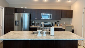 A modern kitchen with dark cabinets, stainless steel appliances, and a central island. - 356 Hood Pl (Wildwood)