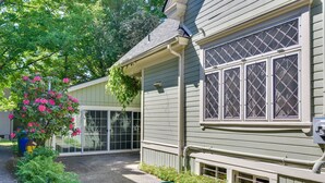 A house with a covered porch, a window with a diamond pattern, and a small window with a grill. - Cozy Portland Studio w/ Electric Fireplace (Portland)