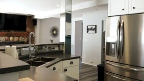 Una cocina moderna con un refrigerador de acero inoxidable, un horno empotrado y un lavamanos.