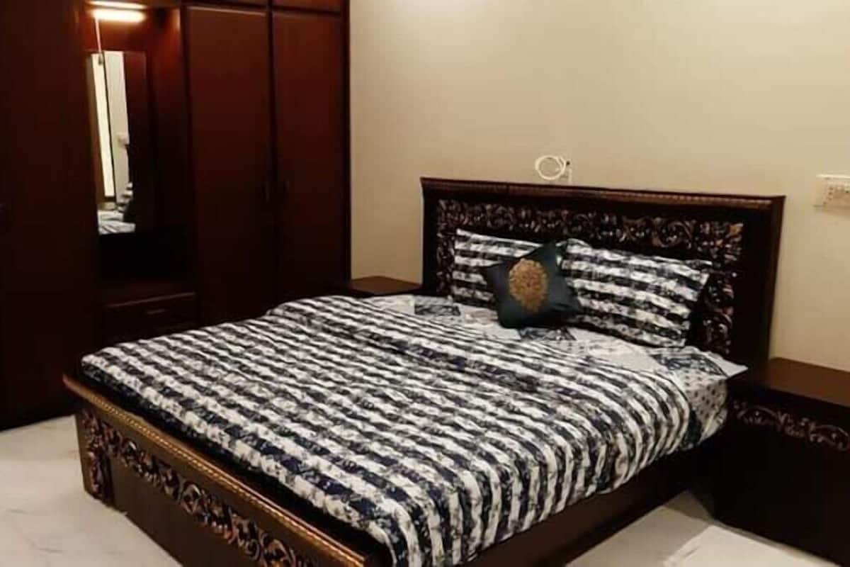 A bedroom with a large bed, a wardrobe, and a nightstand.