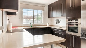 A modern kitchen with dark cabinetry, a stainless steel refrigerator, and a built-in oven. - Beautiful home in Bollullos de la Mitaci (Bollullos de la Mitaci)