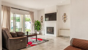 A modern living room with a sofa, a coffee table, a fireplace, and a TV mounted on the wall. - Beautiful home in Bollullos de la Mitaci (Bollullos de la Mitaci)