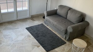 A living room with a grey sofa, a black rug, and a floor lamp.