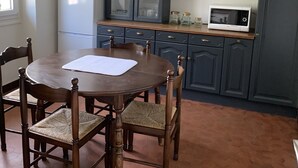 A kitchen with dark cabinets, a white refrigerator, a microwave, and a round wooden table with chairs.