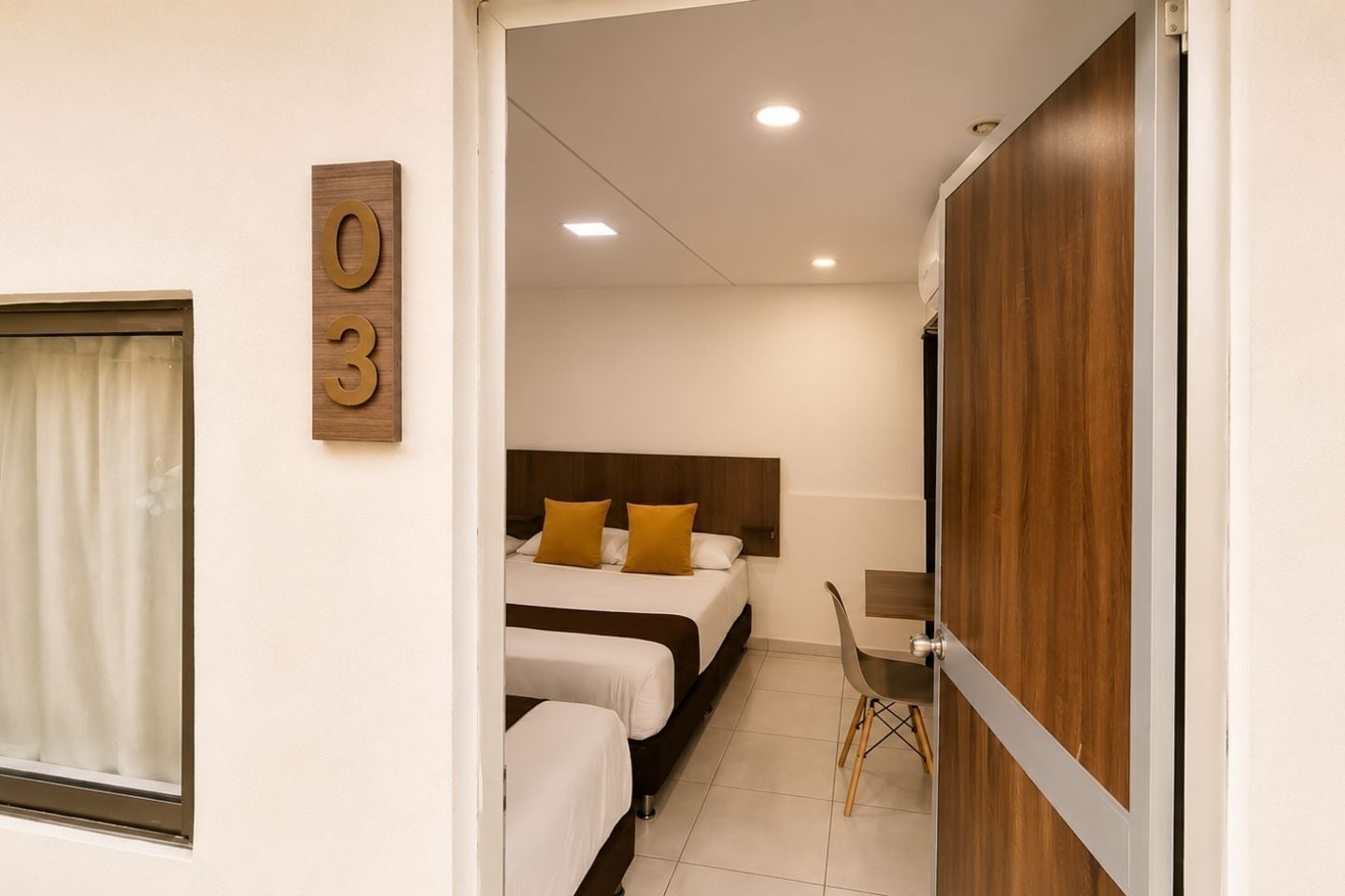 Una habitación de hotel con una cama, una silla y una puerta de madera.