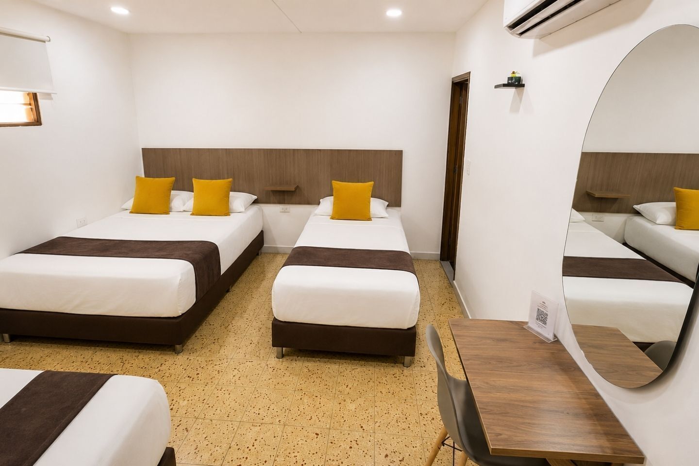 A hotel room with two beds, a wooden headboard, a mirror, and a small table.