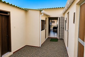 Un couloir avec un sol carrelé, un tapis vert et une porte sur le côté gauche.