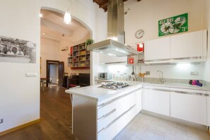 A modern kitchen with white cabinetry, a central island, a microwave, and a clock on the wall.