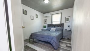 Ein Schlafzimmer mit Bett, Nachttisch und Wand-Klimaanlage.