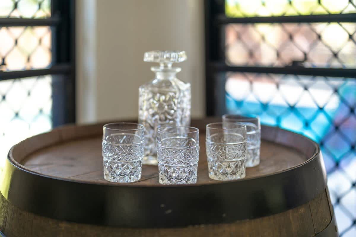 A wooden barrel with crystal glasses and a decanter on top.