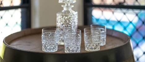A wooden barrel with crystal glasses and a decanter on top.