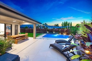 A backyard with a swimming pool, outdoor furniture, and a covered patio area. - Tropical Dreams—Spacious Retreat with Private Pool (Smithfield)