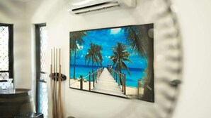 A corridor with a framed painting of a beach scene, a wooden door, and a glass partition. - Tropical Dreams—Spacious Retreat with Private Pool (Smithfield)