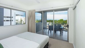 A hotel room with a bed, a ceiling fan, a sliding glass door to an outdoor area with a table and chairs.