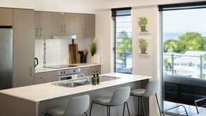 A modern kitchen with a central island, bar stools, and a view of the outdoors.