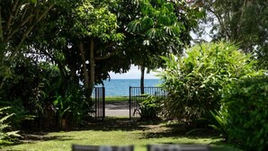 Zona pranzo con tavoli e sedie, vista sul mare e vegetazione lussureggiante.