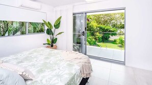 Una camera da letto con un letto, una ventola a soffitto, una grande finestra e vista sul verde.