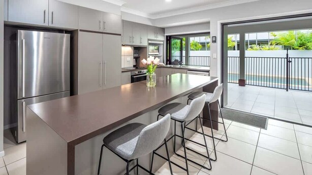 A modern kitchen with a central island, stainless steel appliances, and a view to the outside. - Tropical Pool Sanctuary in Kewarra Beach (Kewarra Beach)