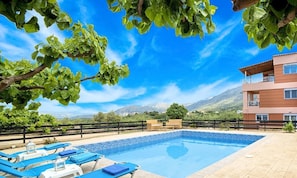 A pool area with lounge chairs, a clear blue sky, and a mountain backdrop. - Peaceful Villa in Kournas,private pool and BBQ,up to 6guests (Κουρνάς)
