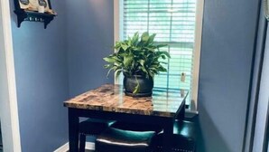 Un coin repas avec une table en bois foncé, deux chaises et une plante en pot.