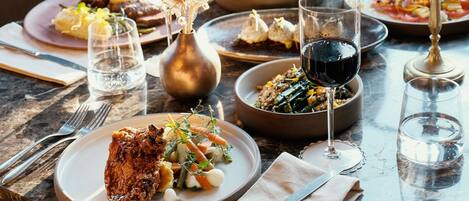 A dining table set with plates of food, glasses, and cutlery.