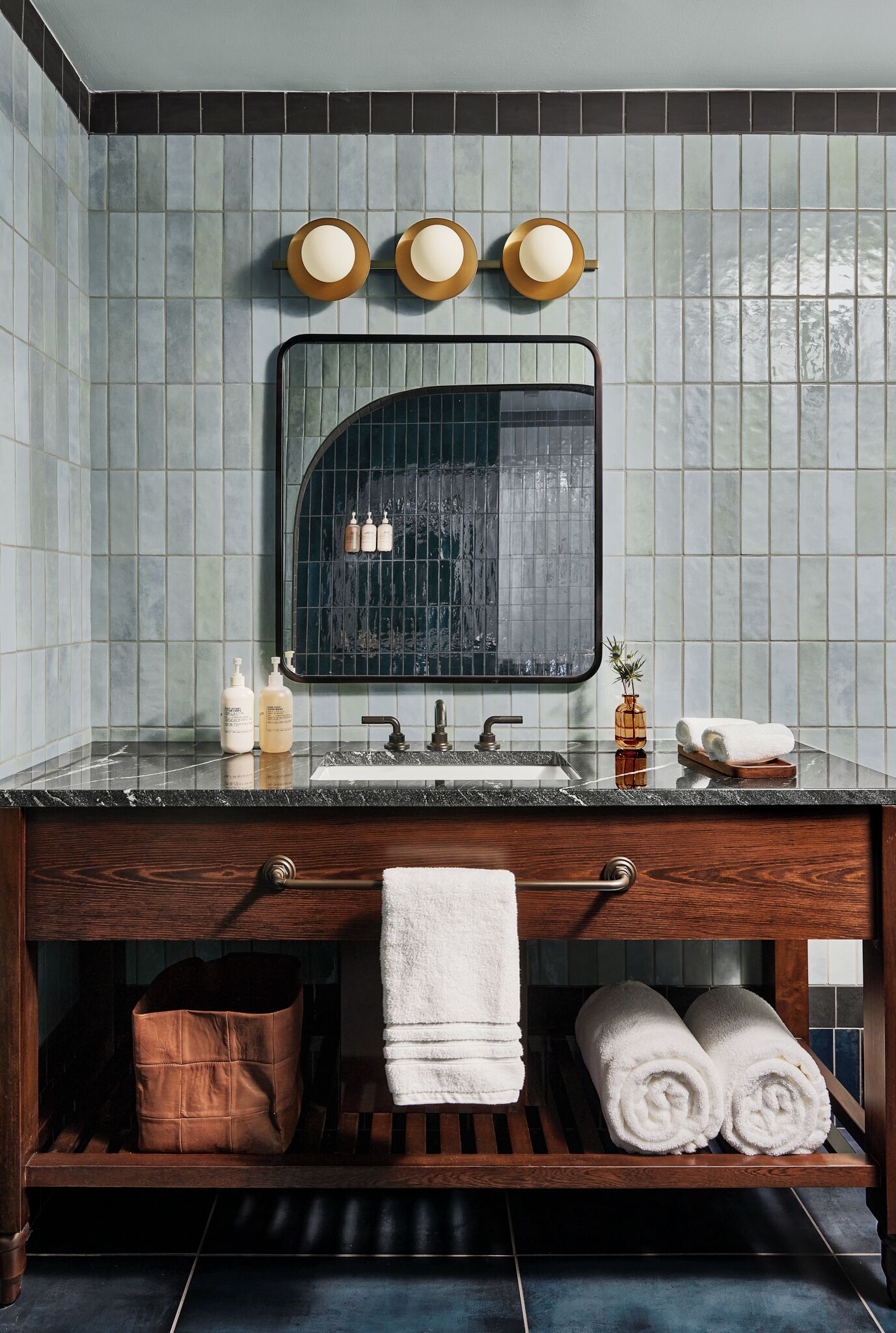 A bathroom with a dark wood vanity, a large mirror, and a tiled backsplash.