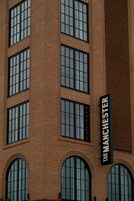 Un edificio de ladrillo con varias ventanas y un letrero que dice "The Manchester".