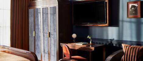 A room with a sofa, a wooden cabinet, a television, and a framed picture on the wall.