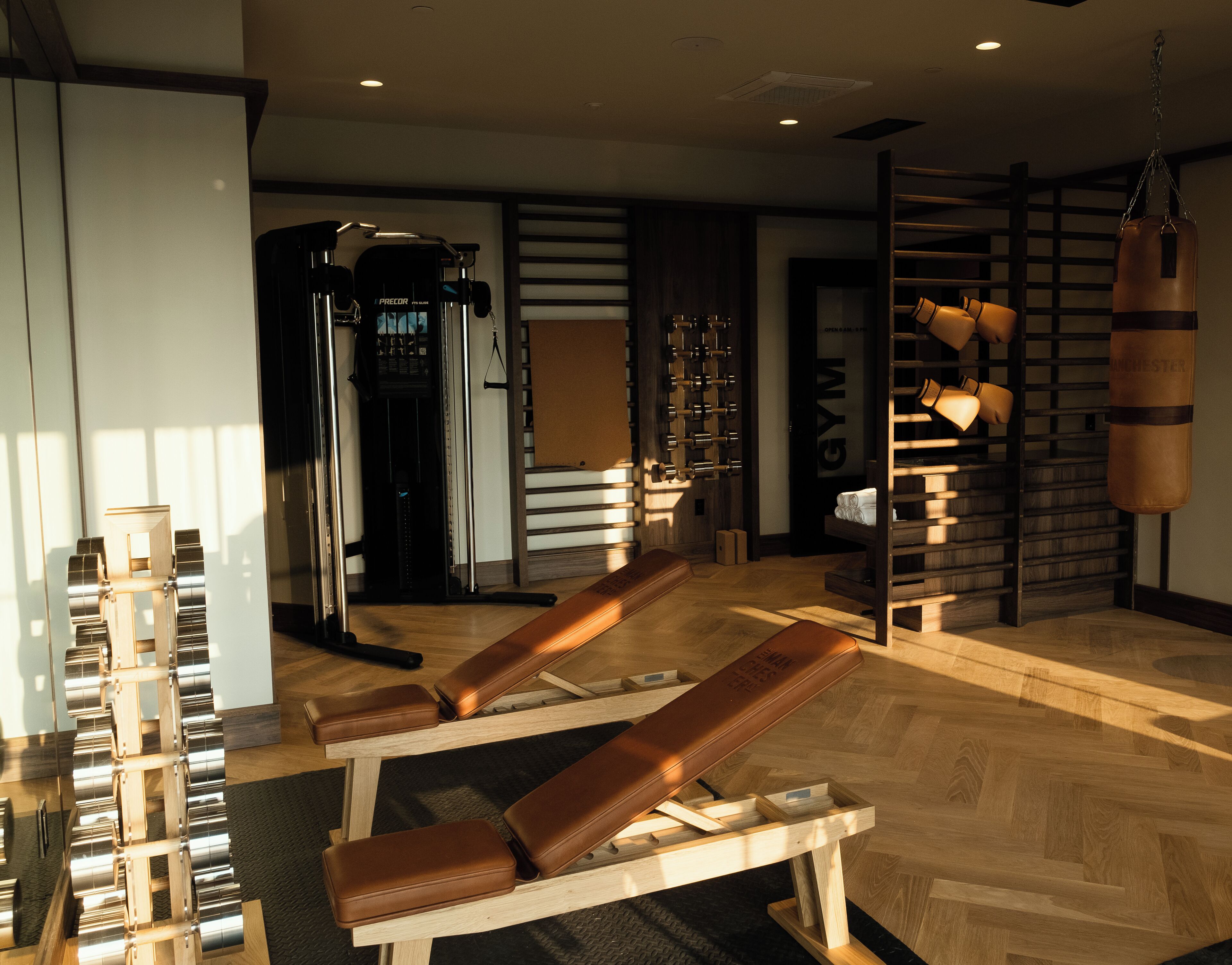 A gym with exercise equipment, a punching bag, and a wooden bench.