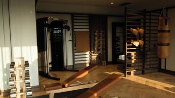 A gym with exercise equipment, a punching bag, and a wooden bench.