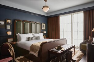 Un dormitorio ordenado con una cama grande, una mesita de noche, una silla y un escritorio.