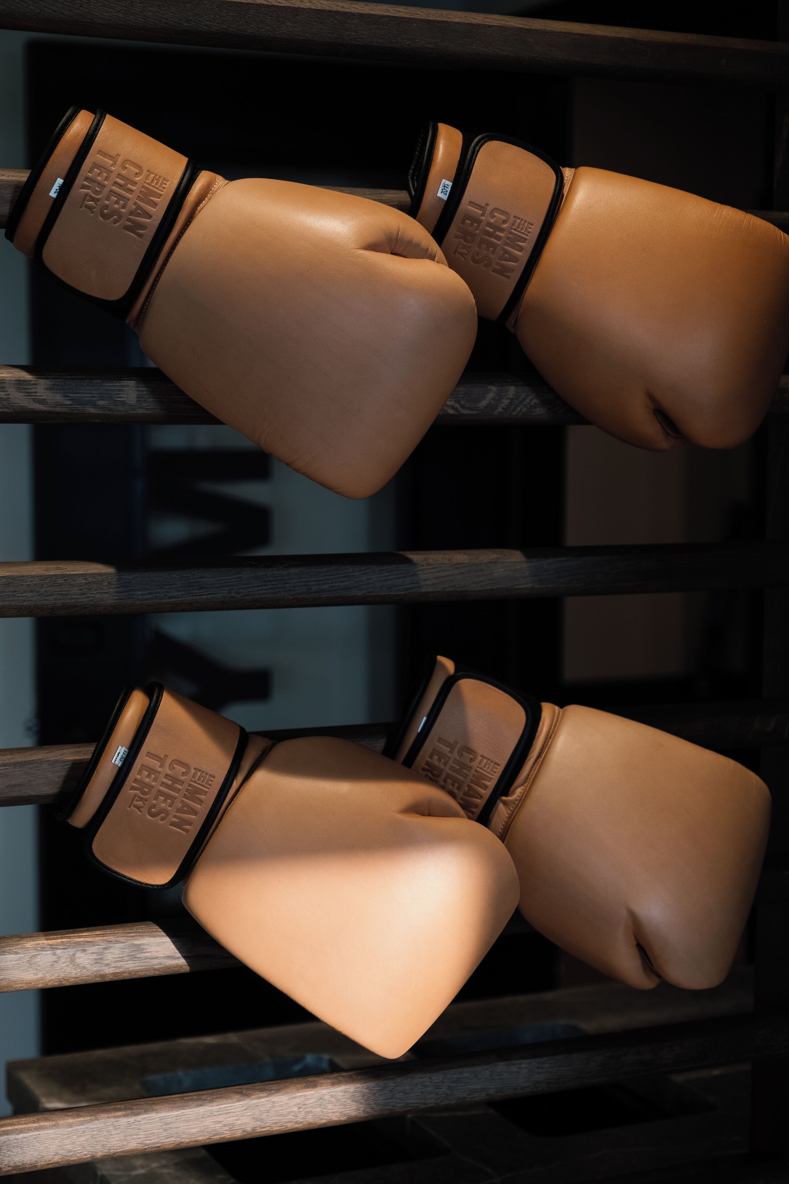 A pair of boxing gloves hanging on a wooden rack.