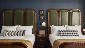 A hotel room with two beds, a nightstand, and a wall-mounted radio.