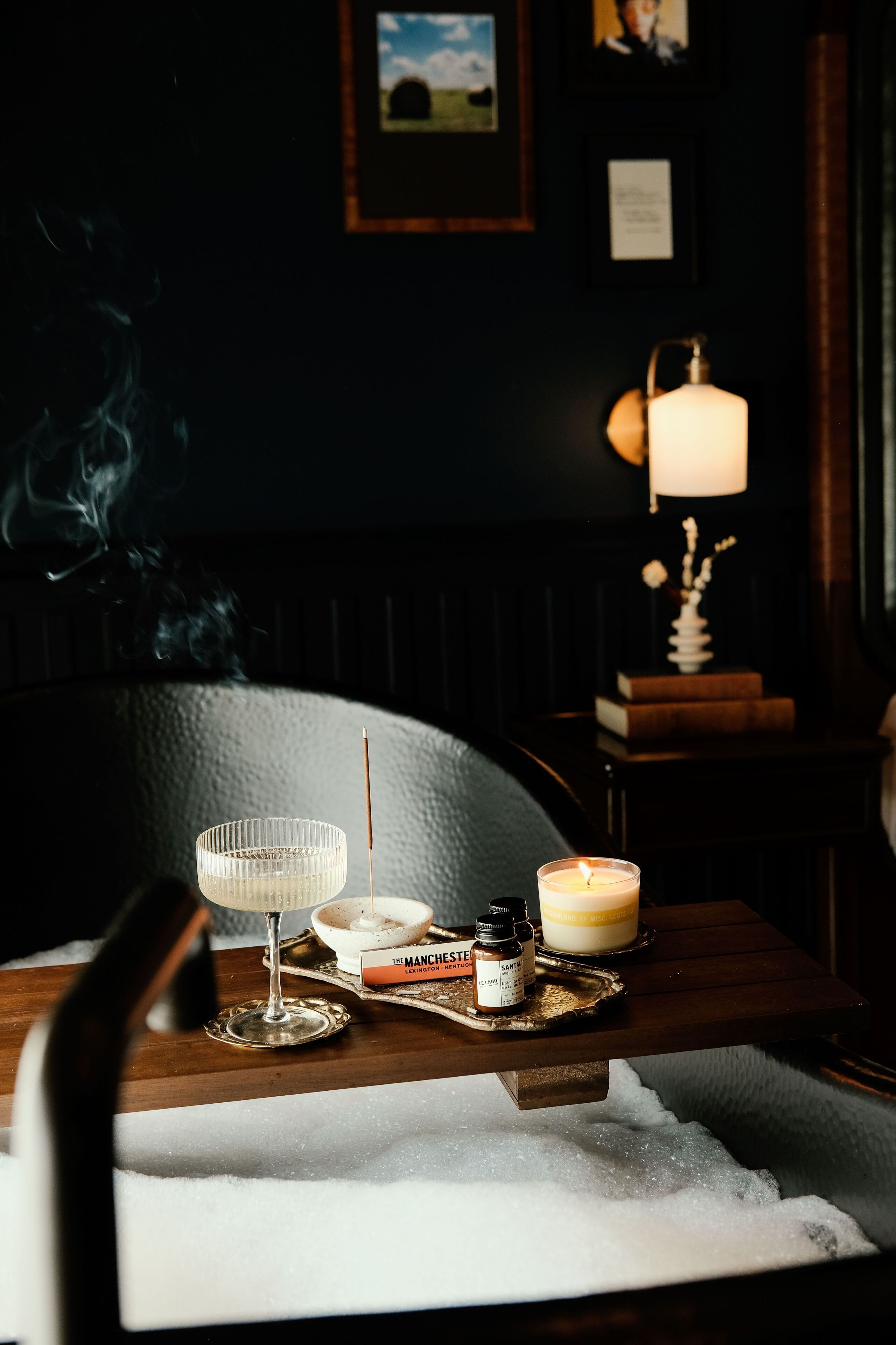 Una habitación acogedora con una mesa de madera, una vela, un libro y un jarrón decorativo.