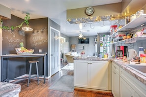 A modern kitchen with a chalkboard wall, wooden bar stools, and a coffee bar.