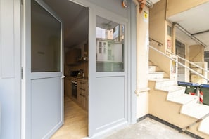 A hallway leading to a kitchen with wooden cabinets and a tiled floor.