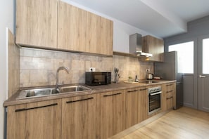 A modern kitchen with wooden cabinets, a stainless steel sink, a microwave, and an oven.