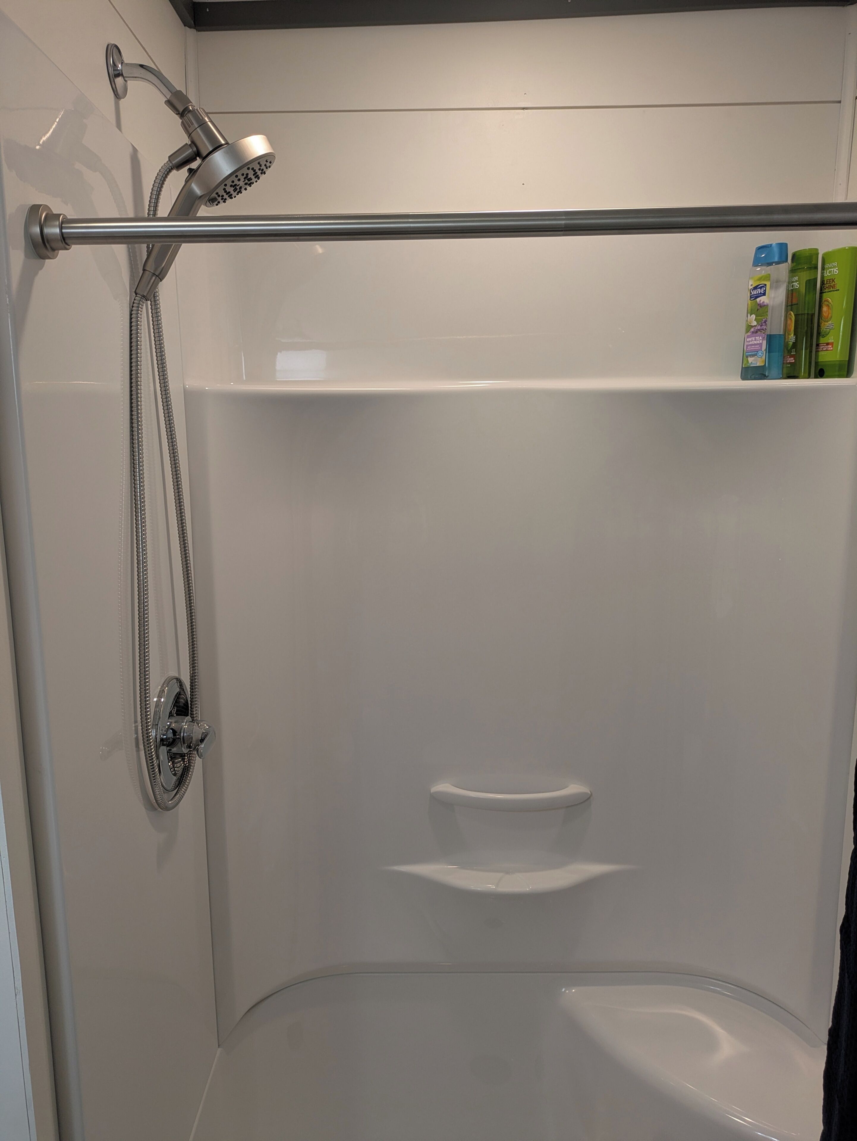 A modern shower area with a handheld showerhead, a handheld shower attachment, and a glass-enclosed tub.