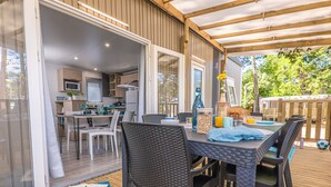 Cocina y comedor integrados con terraza de madera, mesa de comedor con sillas y vistas al exterior.