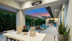 Um pátio externo com piscina, espreguiçadeiras e uma mesa com lanternas decorativas.