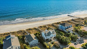 A coastal property with a beach view, featuring a large house with a balcony and a smaller house nearby. - El Mar! Beachfront - Every room is oceanfront with it's own porch & bathroom access! (Folly Beach)