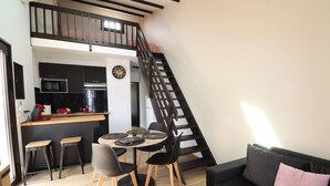 Un espacio habitable compacto con cocina, comedor y una escalera que sube a un nivel superior.