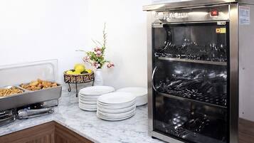 A buffet setup with food containers, plates, and a beverage dispenser.